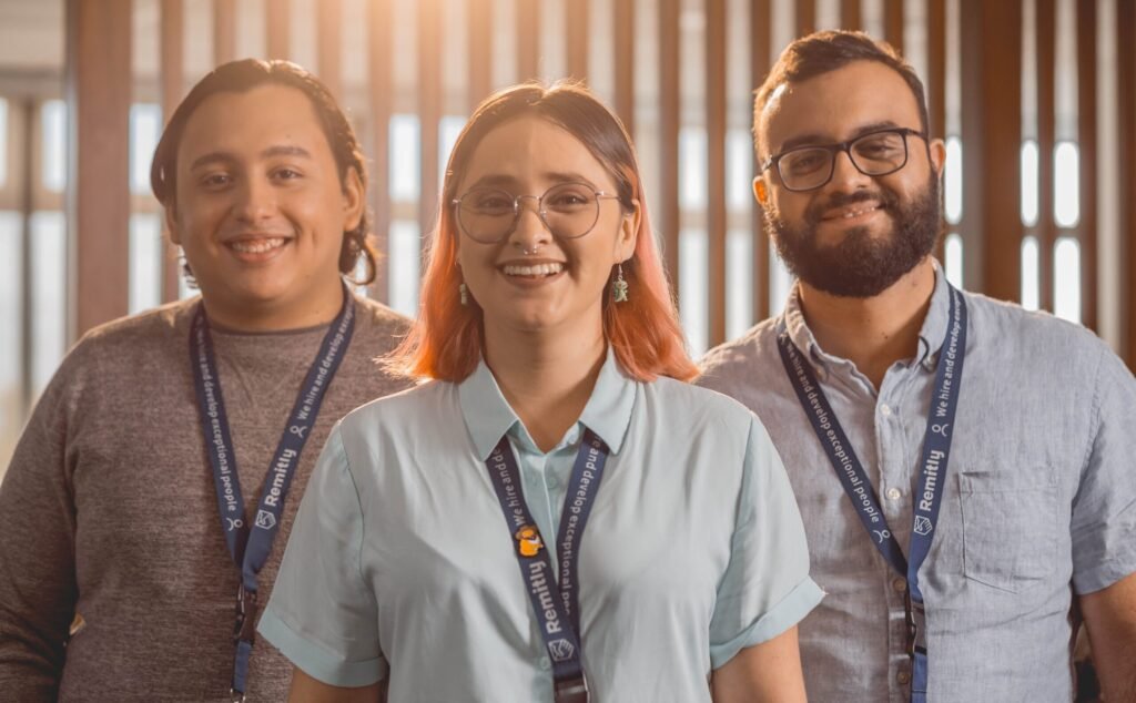Three young professionals smiling confidently in an office setting in Managua, Nicaragua.
